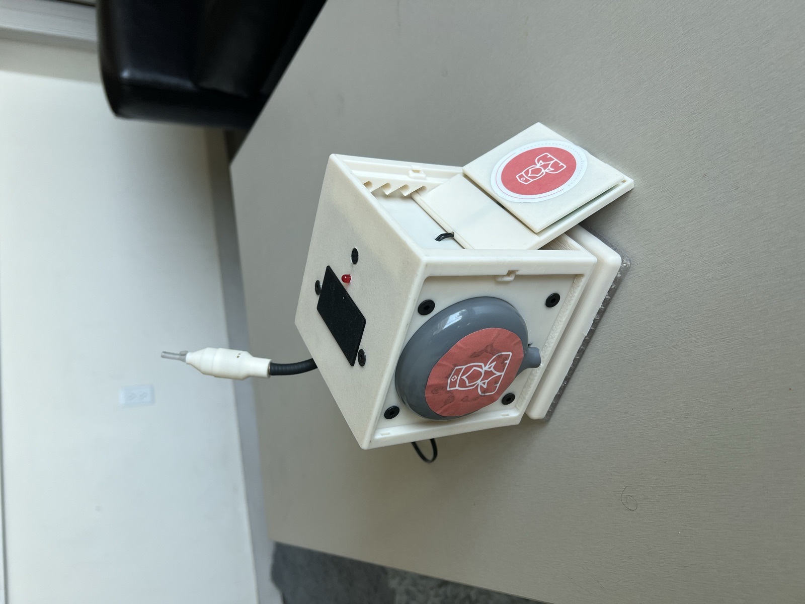 Finished MediFlex Bell prototype: a white 3D-printed cube with the gray-and-red soft button on the front, the incline pad folded out on the side, and the breath-call gooseneck mouthpiece on top